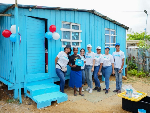 Voluntarios frente a una vivienda recién pintada de azul